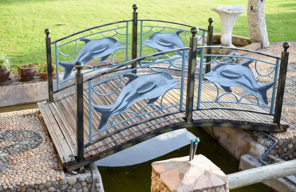 A wooden footbridge with dolphin railings over a water feature